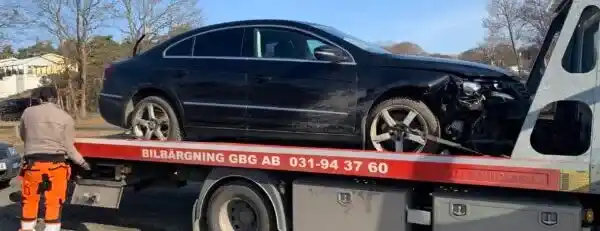Teknisk inspektion av skrotbil där mekaniker kontrollerar motor och dokumenterar skick inför slutlig värdering
